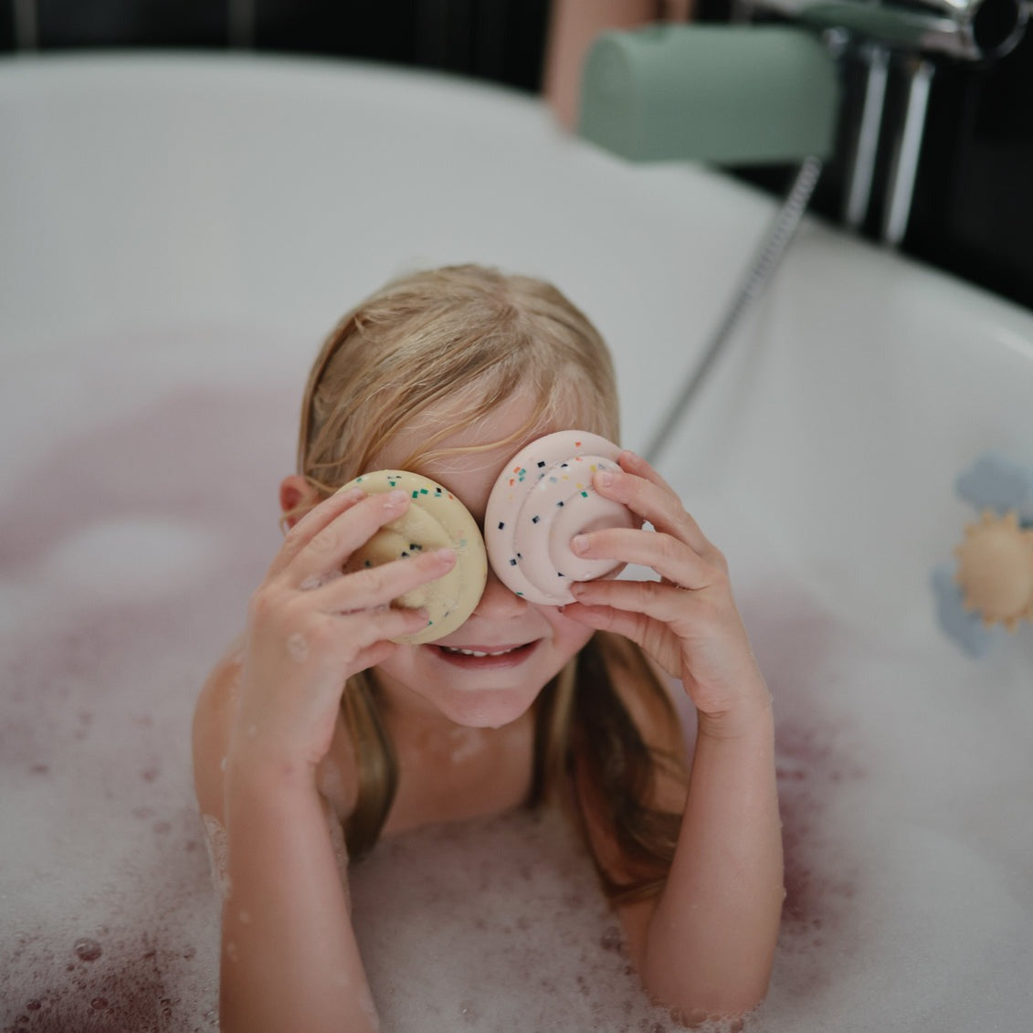 Girl plays in bath with Mushie Mix and Match Cupcake Toy - Original