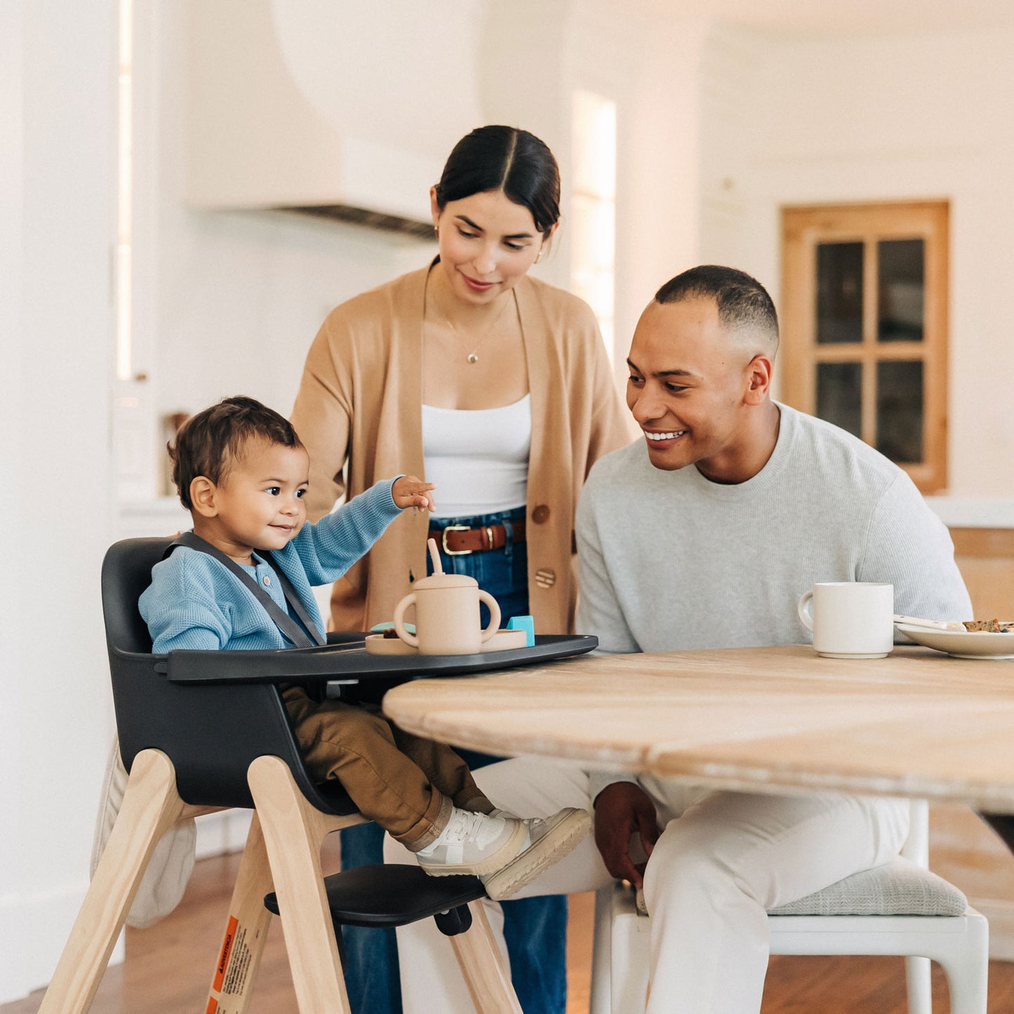 Parents smiling at child sitting in UPPAbaby CIRO High Chair - JAKE (Charcoal)