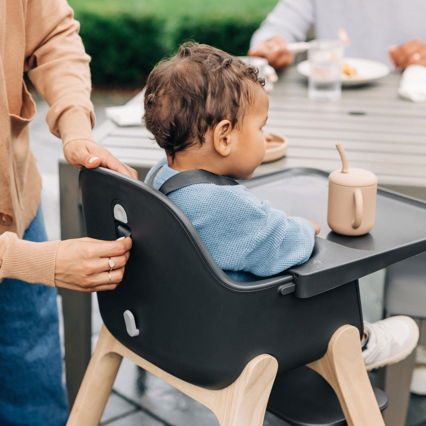 Mom adjusting straps on the back of the UPPAbaby CIRO High chair - JAKE (Charcoal)