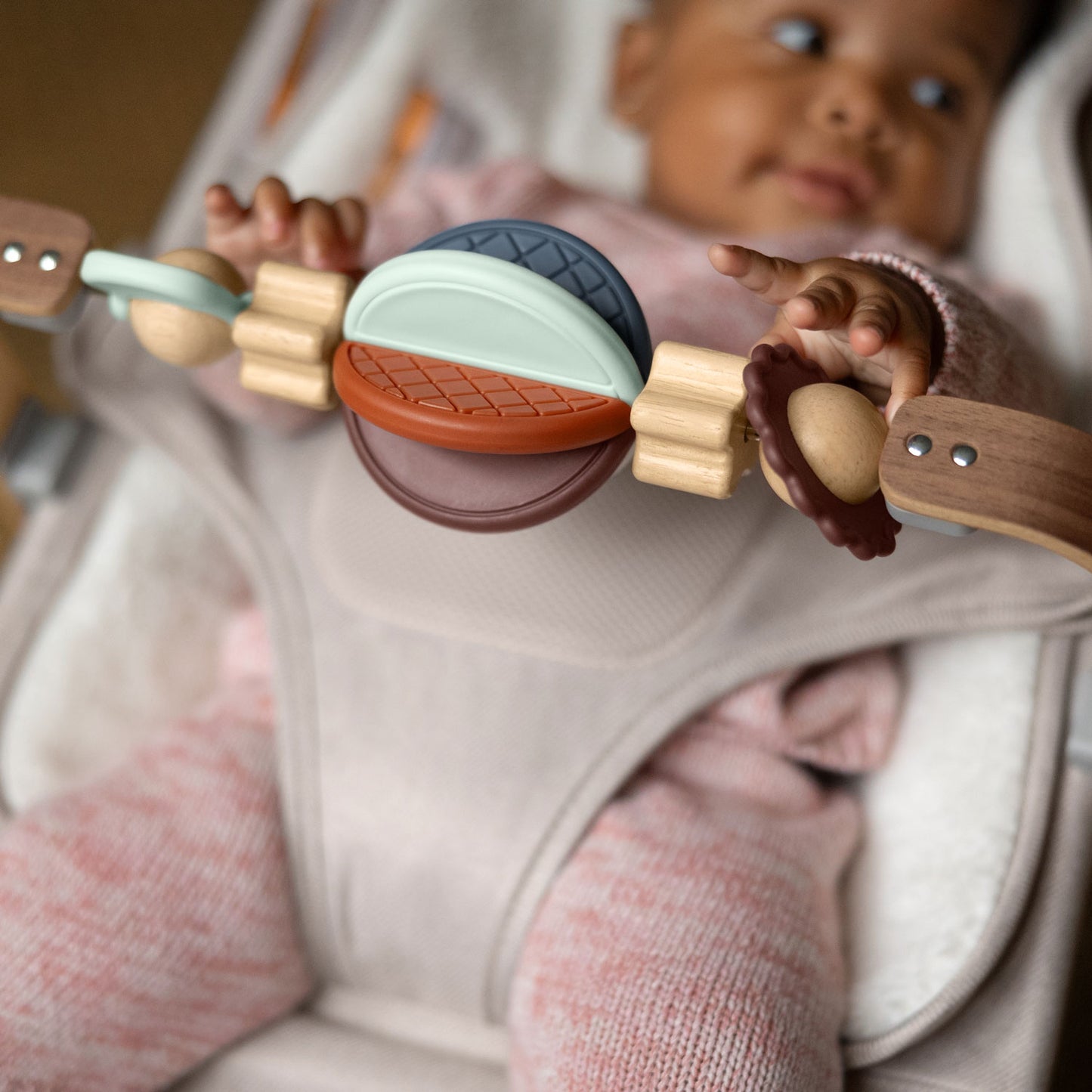 Baby sitting in MIRA bouncer playing with UPPAbaby Wonder Wheel Toy Bar - MIRA accessory attached