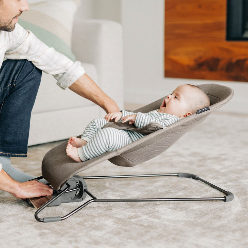 Dad looking at baby sitting in UPPAbaby MIRA 2-in-1 Bouncer and Seat - WELLS (Dark Taupe Melange)