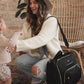Mom smiles at baby with JuJuBe Satchel - Black on her shoulder