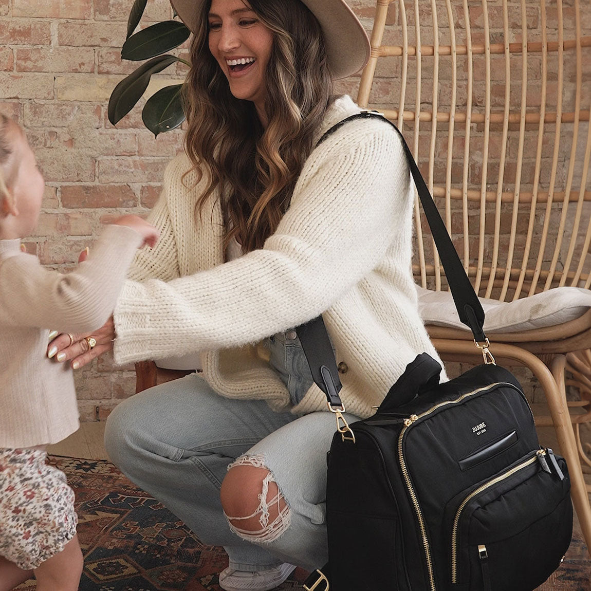 Mom smiles at baby with JuJuBe Satchel - Black on her shoulder