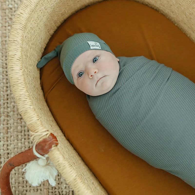 Baby wrapped in Copper Pearl Rib Knit Swaddle Blanket - Moss