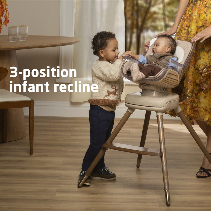 Child smiles at baby sitting in Maxi-Cosi Kiskadee 360 Rotating Highchair - Natural Heritage