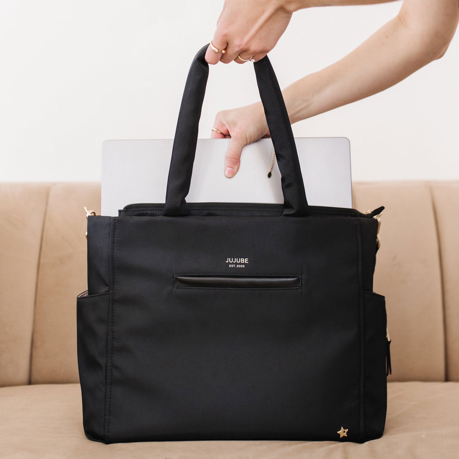 Woman places laptop into JuJuBe Utility-Strap Tote - Black