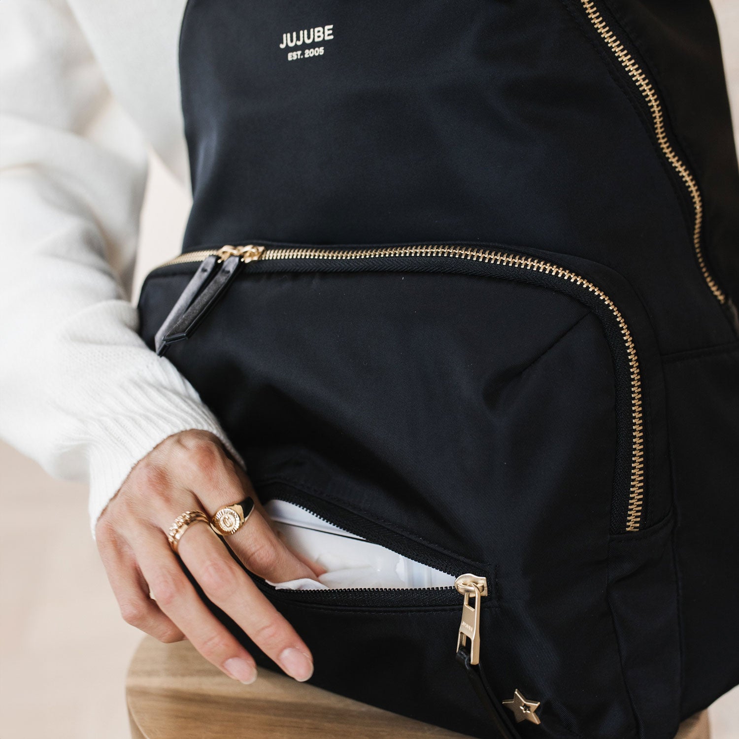 Woman reaches into front pocket of JuJuBe Everyday Backpack - Black