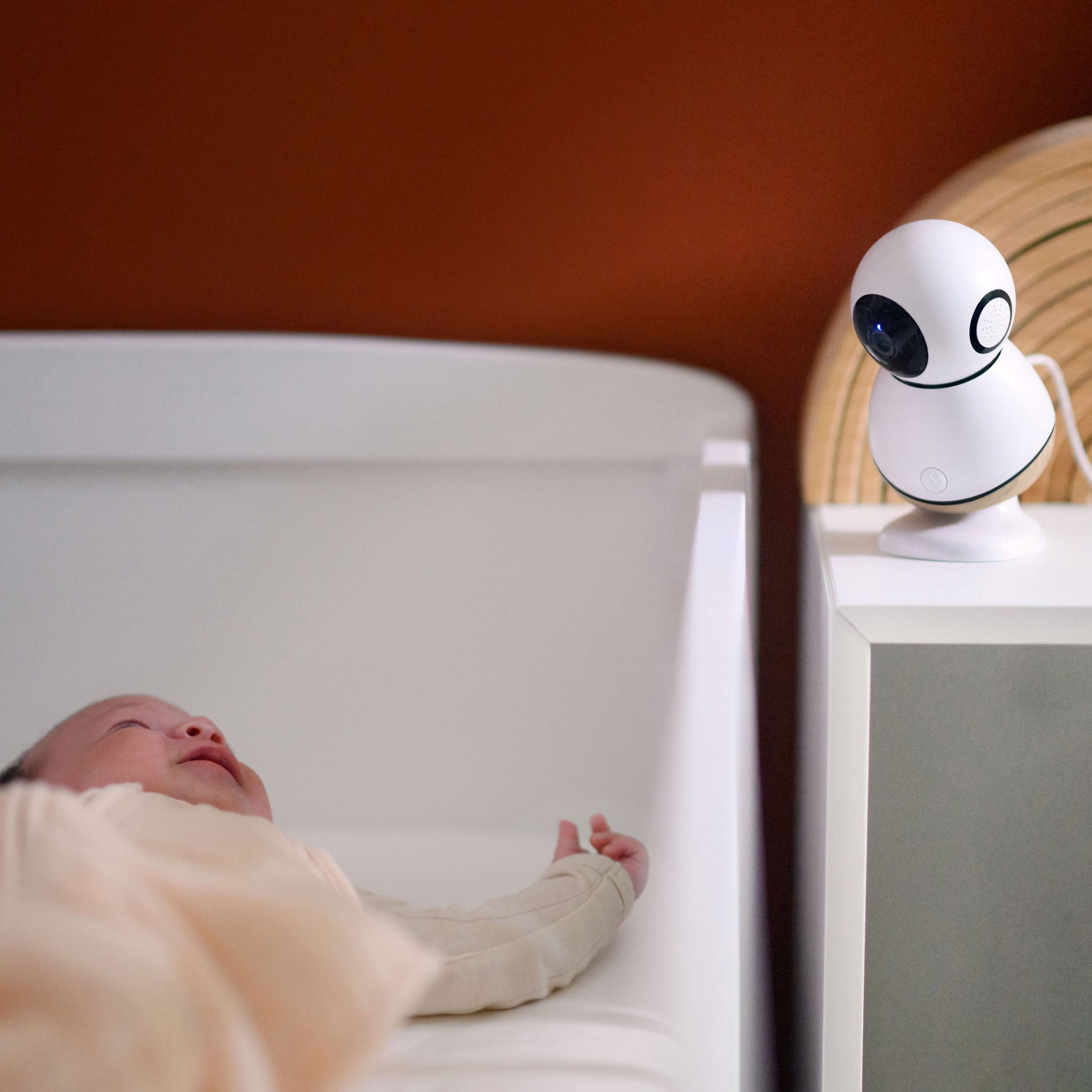 Baby lying in crib with Maxi-Cosi See Pro Monitor - White pointed at him