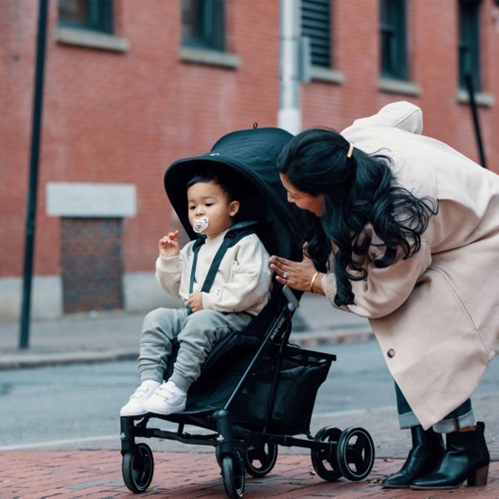 Mom talking to toddler while pushing him in Maxi-Cosi Mara XT Ultra Compact Stroller - Essential Black