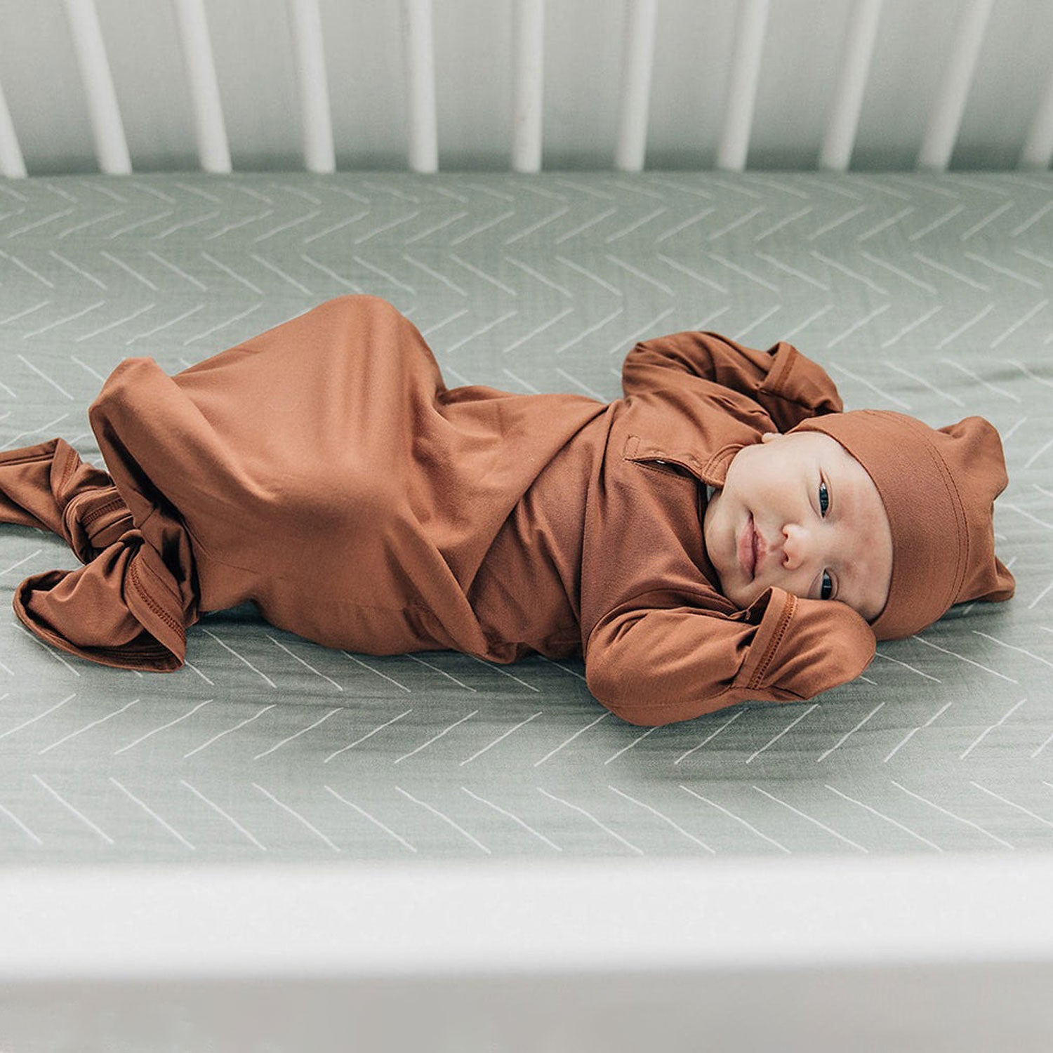 Baby lying on Mebie Baby Muslin Crib Sheet- Desert Sage