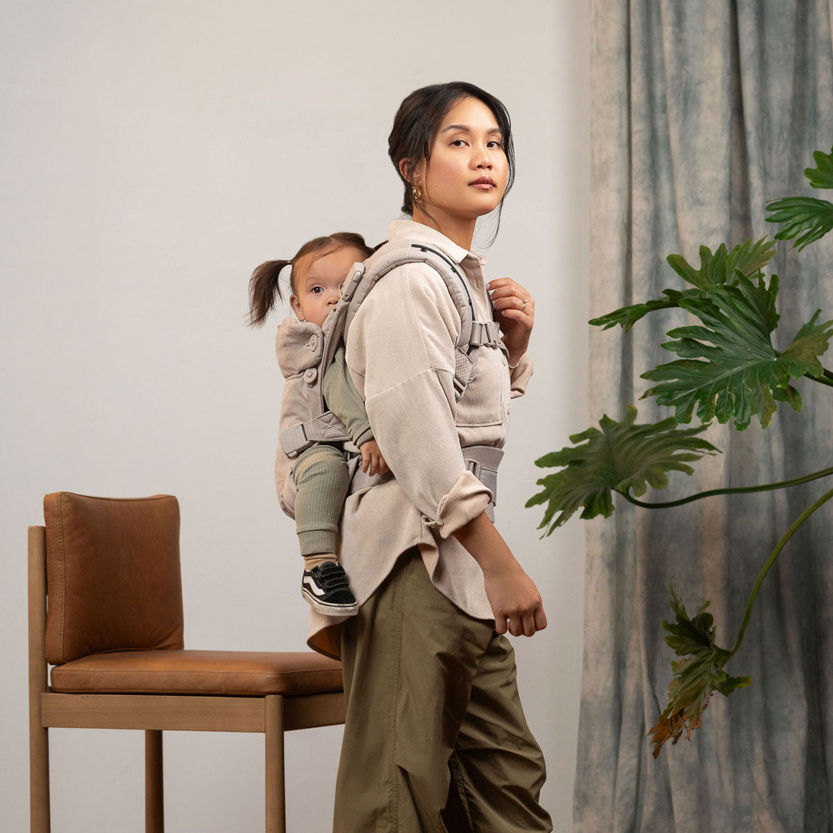 Mom carries toddler on her back in Nuna CUDL Luxe Carrier - Quartz