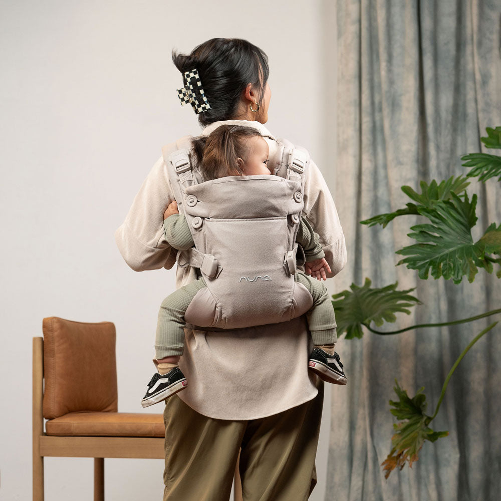 Mom carries toddler on her back in Nuna CUDL Luxe Carrier - Quartz