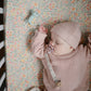 Baby sleeps in crib lying next to Mushie Dog Figurine Teether - Sage