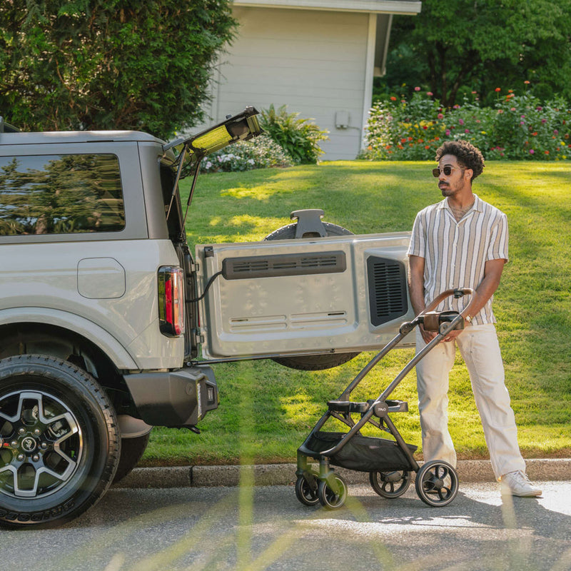 Man stands next to stroller frame of Tavo Maeve + Roscoe 3-in-1 Pet Protection System - Medium Flex - Cognac Stroller