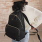Woman puts on JuJuBe Everyday Backpack - Black