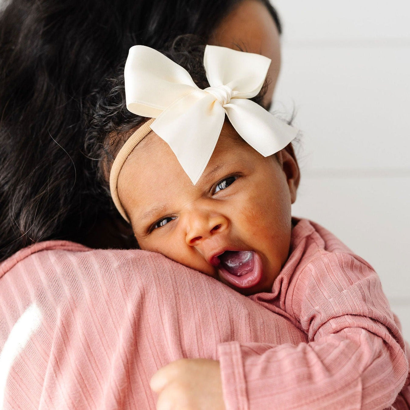 Mom holds baby wearing Lou Lou and Company Satin Bow Headband - Large - Cream