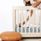 Mom puts pacifier in baby's mouth while baby lies on Lou Lou and Company Ribbed Crib Sheet - Ford