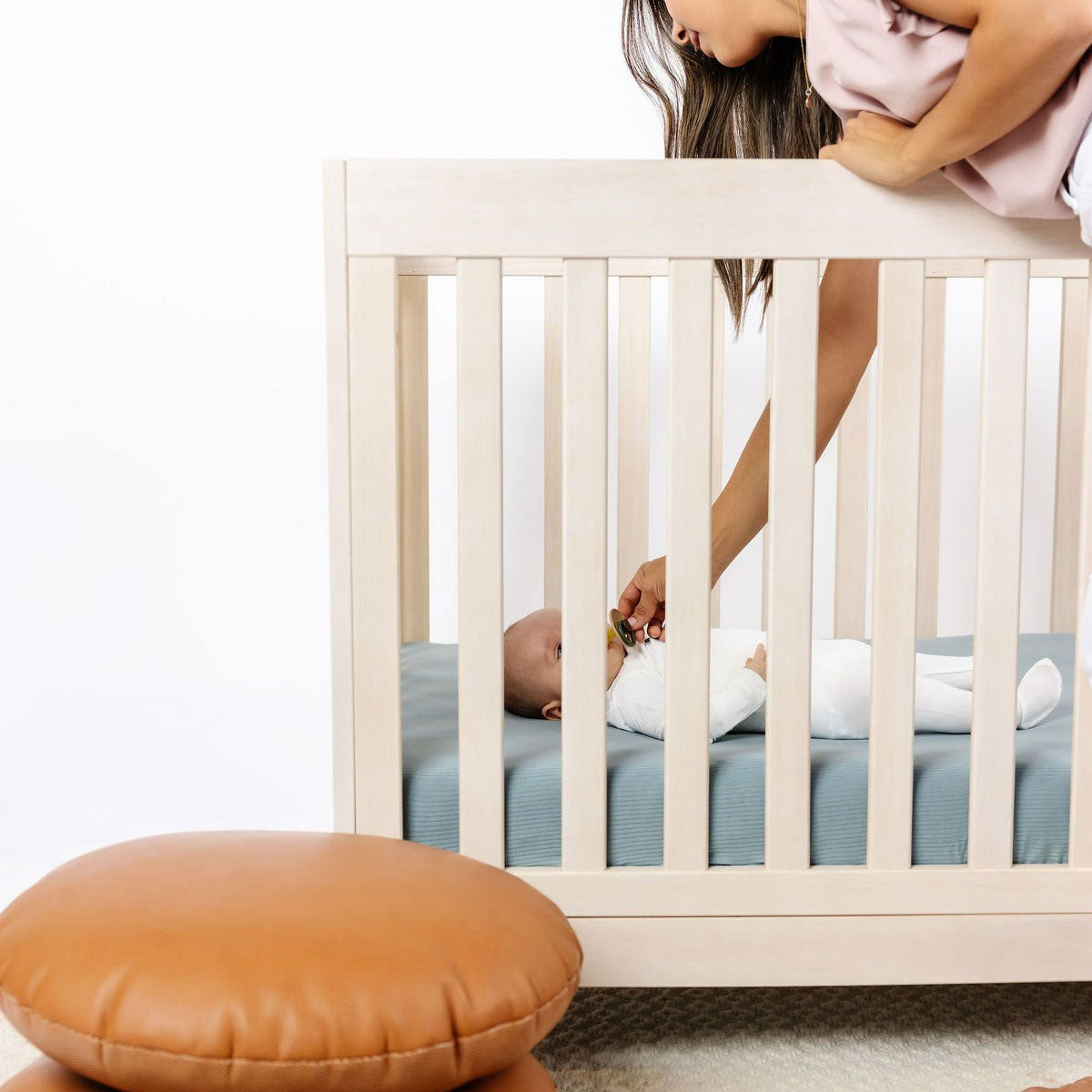 Mom puts pacifier in baby's mouth while baby lies on Lou Lou and Company Ribbed Crib Sheet - Ford