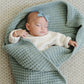Sleeping baby wrapped in Saranoni Receiving Waffle Knit Blanket - Elm