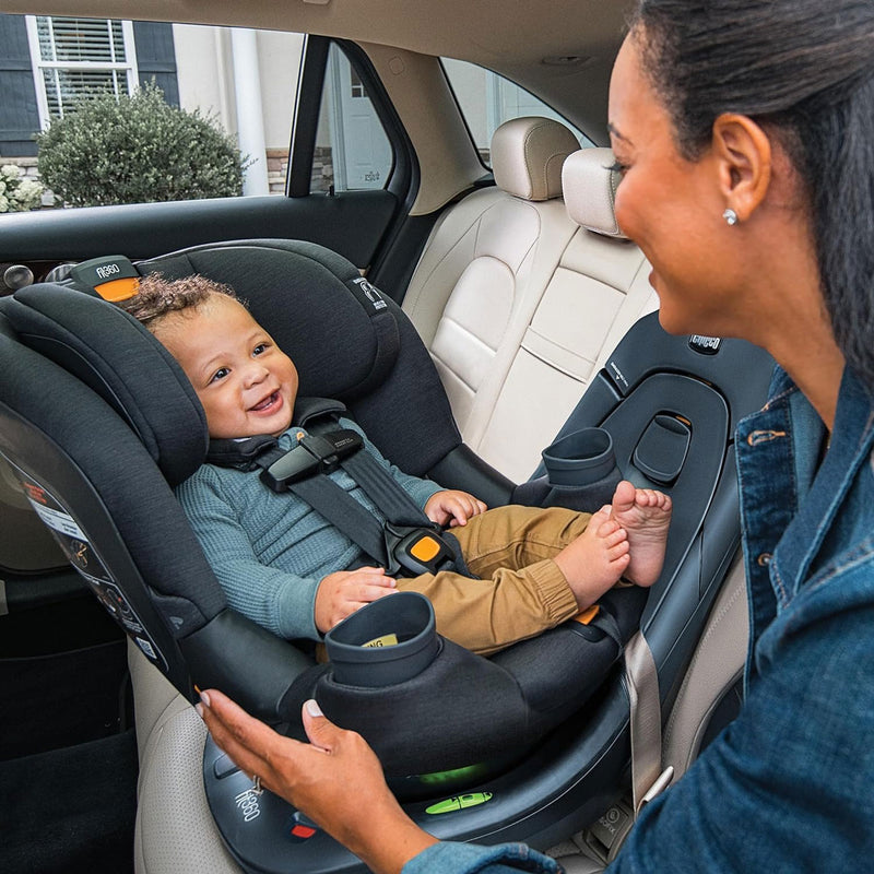 Mom putting baby into Chicco Fit360 ClearTex Rotating Convertible Car Seat - Black