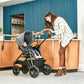 Woman smiles at baby sitting in Chicco Corso LE Modular Travel System - Hampton