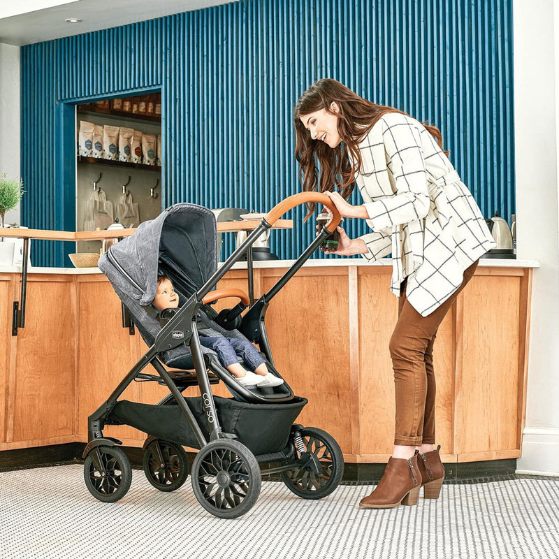 Woman smiles at baby sitting in Chicco Corso LE Modular Travel System - Hampton