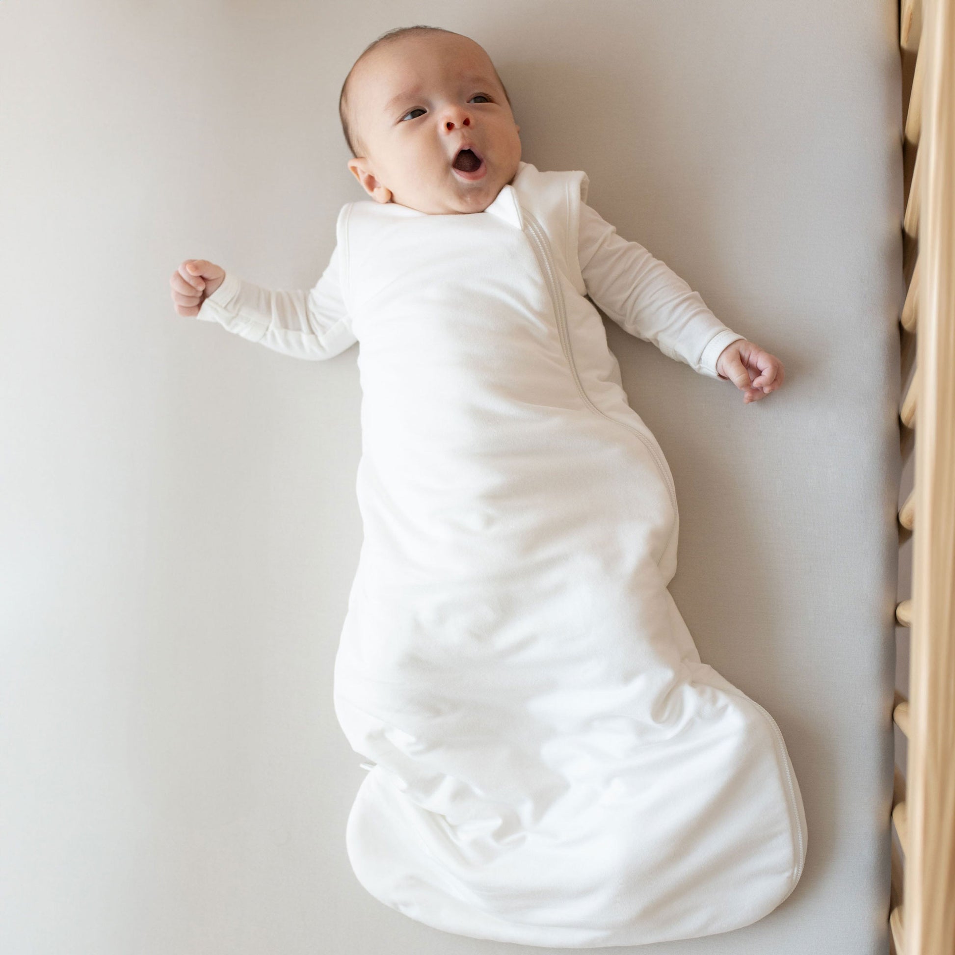 Newborn baby lays in crib in Kyte BABY Sleep Bag - Cloud - 1.0 Tog