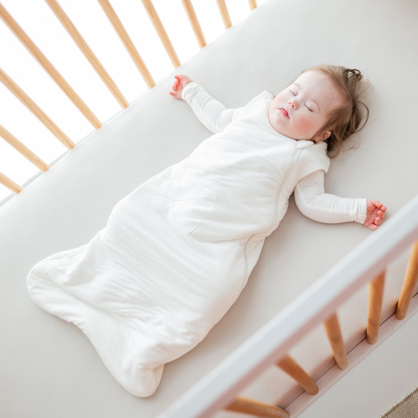 Baby girl sleeps in crib in Kyte BABY Sleep Bag - Cloud - 1.0 Tog