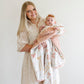 Mom holds baby wrapped in Saranoni Receiving Minky / Lush Blanket - Bows