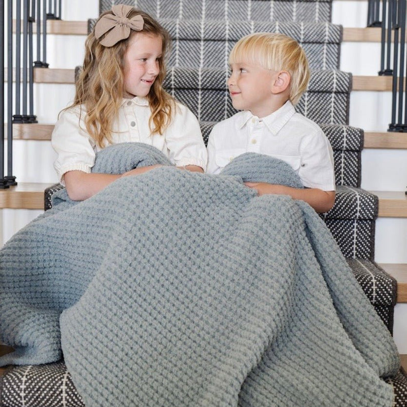 Kids snuggle together in Saranoni Waffle Knit Toddler Blanket - Elm