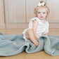 Toddler sits on Saranoni Waffle Knit Toddler Blanket - Elm
