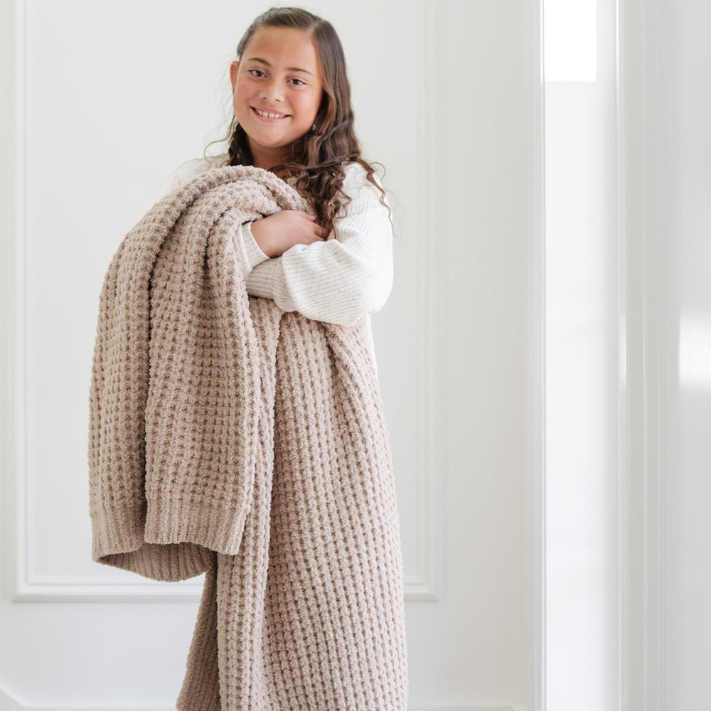 Little girl holds Saranoni Waffle Knit Toddler Blanket - Wheat