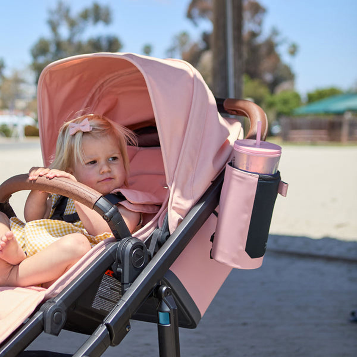 Baby sits in stroller with Veer Catch All - Rose Quartz attached