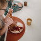 Kids eating food from Mushie Silicone Suction Plate - Blush