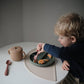 Little boy eating fruit from Mushie Silicone Suction Plate